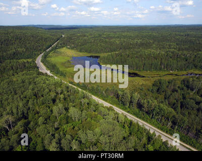 Luftaufnahme von eine Straße durch den Wald und Berge mit Moor oder Sumpf, Quebec, Kanada Stockfoto