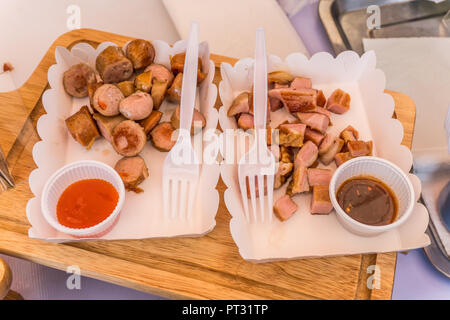 Gebratene Würstchen und Speck in Geschenkpapier mit Sauce Stockfoto