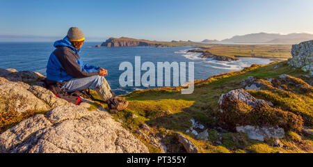 Mann mit Blick auf die Küstenlinie an einem klaren Morgen, Lage: Halbinsel Dingle in Co Kerry, Irland, in der Nähe von Waymont Graigue, 52, 151437, -10, 475927 Stockfoto