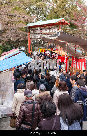 Japanische neues Jahr, Shogatsu. Avenue von Marktständen, mit Torri Tor, mit Menschen zu Shinto Yasaka Schrein für traditionelle erster Besuch verpackt. Stockfoto