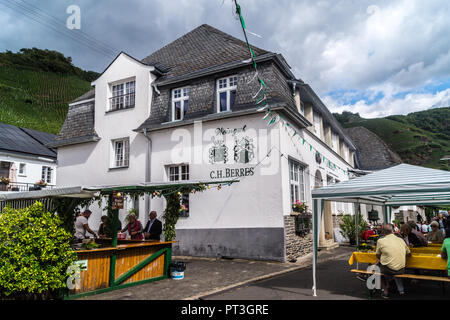 Weingut von Weingut C.H. Berres mit Weinberg Ürziger Würzgarten darüber hinaus, während die Straße Weinfest, Ürzig, Mosel, Rheinland-Pfalz, Deutschland Stockfoto