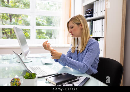 Junge Geschäftsfrau hält Ihre schmerzhafte Handgelenk im Büro Stockfoto