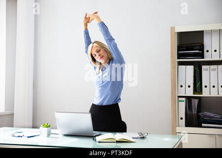 Schöne junge geschäftsfrau recken ihre Arme am Arbeitsplatz Stockfoto