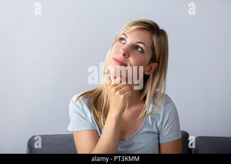 Portrait einer jungen Frau nachdenklich auf grauem Hintergrund Stockfoto