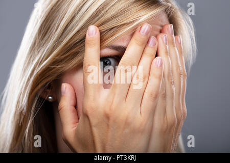 Nahaufnahme von einem erschrockenen Frau spähen durch die Finger Stockfoto