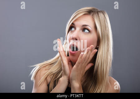 Portrait einer jungen Frau entsetzt auf grauem Hintergrund Stockfoto