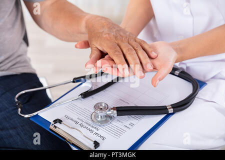 Der Arzt, der Leitende Patienten Hand über Zwischenablage mit Stethoskop Stockfoto