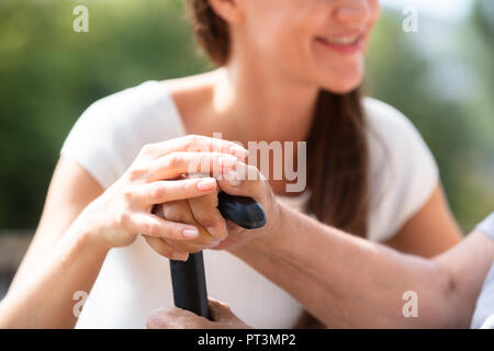 Nahaufnahme von einer Tochter Hand Unterstützung von Ihrem Vater Holding Walking Stick Stockfoto