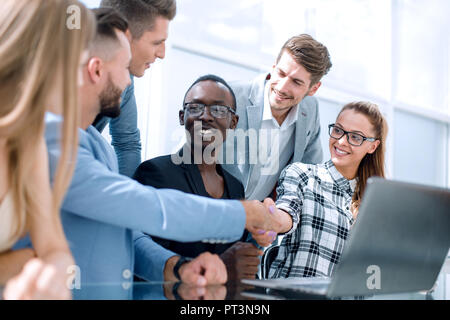 Gruppe von lächelnden multikulturellen Business Partner am Tisch sitzen mit Laptops und Papiere während der Tagung in modernen Büro Stockfoto
