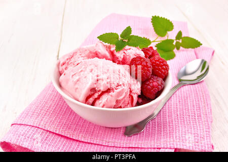 Eis crimson mit Himbeeren, Beeren und Minze in weiße Schüssel, einen Löffel auf rosa Handtuch auf Holzbrett Hintergrund Stockfoto