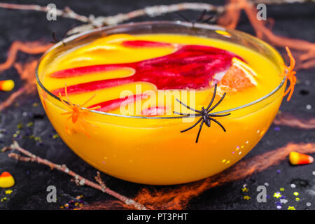 Ghoul orange Punch mit blutigen Eis Hand in eine Glasschüssel auf dunklen halloween Hintergrund Stockfoto