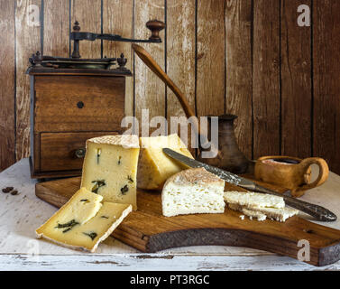 Stillleben mit einer Tasse Kaffee und Käse. Lecker. Vintage alte Kaffeemühle. Käse mit Schimmel. Stockfoto