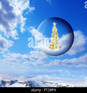 Geschmückten Weihnachtsbaum in Glaskugel schwebend in der Luft über schneebedeckte Berge Landschaft und sonnigen Himmel Stockfoto