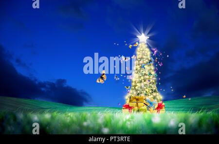 Konzeptionelle verziert glänzend Weihnachtsbaum auf grüne Landschaft und fliegende Schmetterlinge über klaren Nachthimmel Stockfoto
