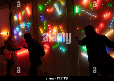 Drei Menschen genießen Neonlicht-Anzeige in der Leeds Light Night West Yorkshire, England, Großbritannien. Stockfoto