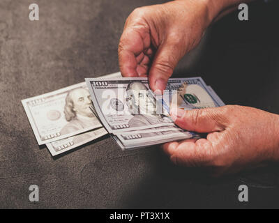 Zählen US-Währung. Alte Frau zählt Geld. Neue Dollar in die Hände falten. Nähe zu sehen. Unternehmen, Finanzen, Einsparungen Konzept. Stockfoto