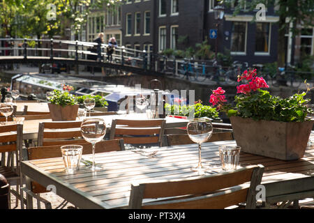 Amsterdam Restaurant Cafe Tabellen für Mahlzeiten im Freien mit Glaswaren und Blick auf die Gracht Bridge im Hintergrund einstellen Stockfoto