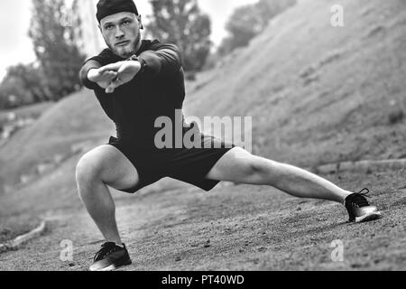 Muskulöse Sportler Stretching vor dem Sport Ausbildung an der Straße im City Park Stockfoto