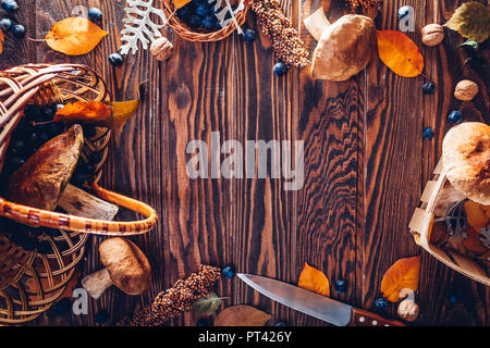 Steinpilze in Korb mit Beeren und Nüssen auf hölzernen Tisch. Herbst Ernte. Versammelt Herbst Ernte. Raum Stockfoto