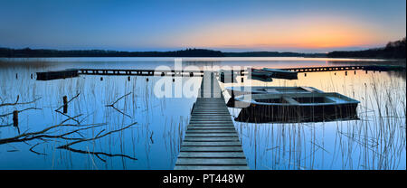 Deutschland, Mecklenburg-Vorpommern, Schaalsee, Pier mit Fischerbooten im Schilf, Sonnenuntergang Stockfoto