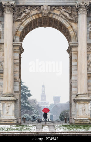 Eine Frau mit roten Regenschirm bewundert die Ansicht des Sempione Park während einer Schneefall, Mailand, Lombardei, Italien, Europa, Stockfoto