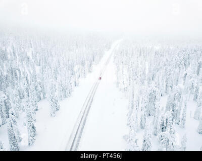 Luftaufnahme von Auto auf der schneebedeckten Straße in den eisigen Wald, Pallas-Yllastunturi Nationalpark, Muonio, Lappland, Finnland Stockfoto