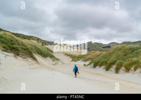 Frau zu Fuß in Richtung Sandfly Bay an einem bewölkten Sommertag, Dunedin, Otago Region, South Island, Neuseeland, Stockfoto