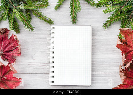 Blick von oben auf ein Weihnachten Holz- Hintergrund aus Tannenzweigen, einen Kegel und einem Notizblock. Neues Jahr Hintergrund Stockfoto