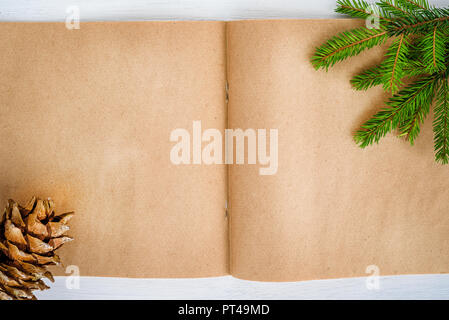 Leere notepad Kraftpapier auf einem weißen Hintergrund. Weihnachten Komposition - Kegel und Tannenzweigen Stockfoto