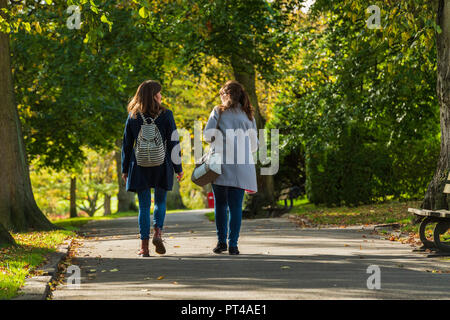 Valley Gardens, Harrogate, Yorkshire, England - Rückansicht 2 Junge weibliche Freunde reden & Wandern am Baum - Pfad in einem schönen, ruhigen Park gesäumt. Stockfoto