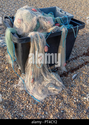 Nylon Fischernetze Verschütten von einem grauen Kunststoff Container auf einem Kieselstrand Stockfoto