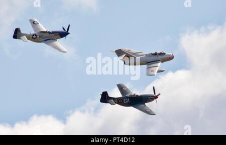 Mikoyan-Gurevich MiG-15 UTI fliegen in Formation mit 2 North American P-51D Mustang am IWM Duxford Schlacht von Großbritannien Airshow auf dem 23/9/18 Stockfoto