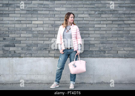 Modische Frau trägt eine rosa Jacke und hüftjeans. Stockfoto