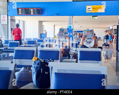 Bodrum, Türkei - Juli 7, 2018. Die Passagiere in einem Terminal eines türkischen Flughafen Lesen von Zeitungen warten. Flughafen Bodrum. Provinz Mugla, Türkei. Stockfoto