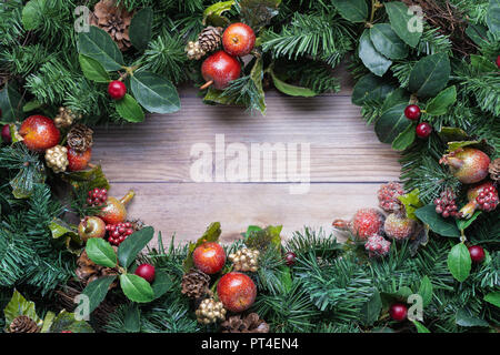 Weihnachten grün Kranz Hintergrund mit glitzerndem apple Ornamente auf rustikalem Holz Stockfoto