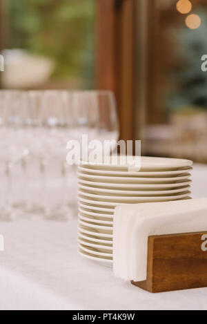 Gläser und weiße Platten auf einem Tisch im Restaurant. Stilvolle ware für ein festliches Buffet Rezeption Stockfoto