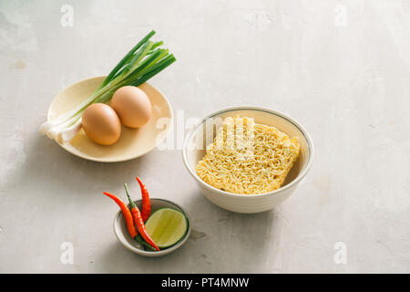 Instant Nudeln in der Schüssel und Gemüsebeilagen auf Stein Hintergrund. Schnell & einfach essen Konzept. Stockfoto