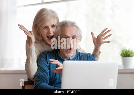 Senior reifes Paar durch gute unglaubliche Nachricht überrascht aufgeregt, unerwarteten Gewinnen, riesigen Shopping Verkauf Angebot auf der Website, erstaunt ältere im mittleren Alter fa Stockfoto