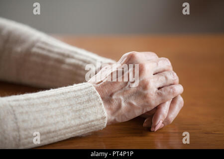 Nahaufnahme der reifen alten weiblichen Person faltigen Hände mit Adern am Tisch, im mittleren Alter ältere ältere Frau mit verschränkten Armen beten als Konzept Stockfoto