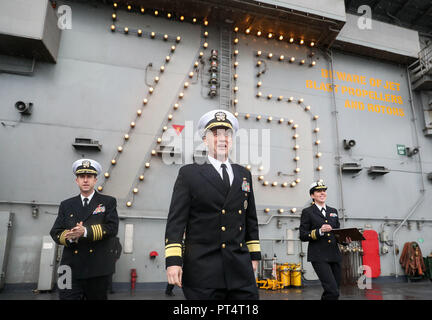 Der Rückadmiral Eugene H. 'Gene' Black, Commander, Carrier Strike Group 8 (Mitte), und Kapitän Nichola J. Denna, Kommandant (links), auf dem Flugdeck des US-amerikanischen Flugzeugträgers USS Harry S. Truman, der während eines Besuchs in Portsmouth in Stokes Bay, Hampshire, eintrifft. Stockfoto