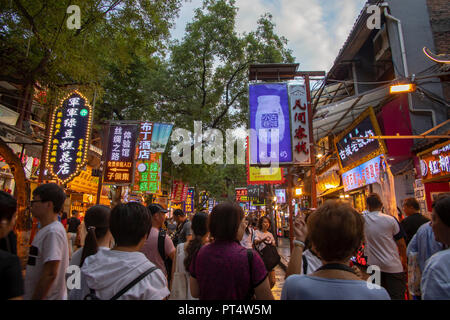 Xi'an, China - 10. September 2018: die Besucher in der überfüllten Hui muslimischen chinesischen Nachbarschaft Straße Markt bei Nacht mit beleuchteten Leuchtreklamen. Stockfoto