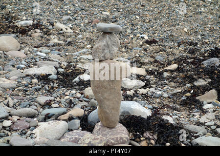 Drei Steine balancieren Übereinander auf einen Kiesstrand in der Nähe der Mündung an Traeth Dulas auf der Insel Anglesey Coastal Path, Wales, UK. Stockfoto