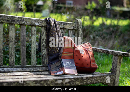 Tasche Schal und buchen Sie links auf einer Bank im Park. Stockfoto