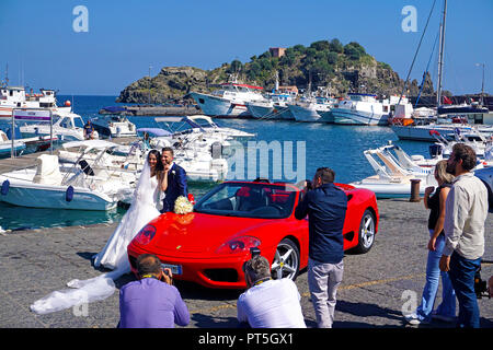 Foto Session, Brautpaar mit Ferrari am Hafen von Aci Trezza, hinter der Insel Lachea, Hauptinsel der Zyklopen, Catania, Sizilien, Italien Stockfoto