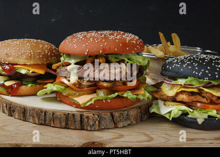 Drei große schöne Burger mit Brötchen in verschiedenen Farben und verschiedenen Füllungen, Hühnchen, Fleisch Patty und Steak. Stockfoto