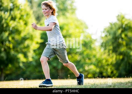 Junge läuft im Park, ein Lächeln auf den Lippen. Stockfoto