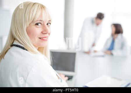 Portrait von Frau Doktor schaut über die Schulter und lächelt. Stockfoto
