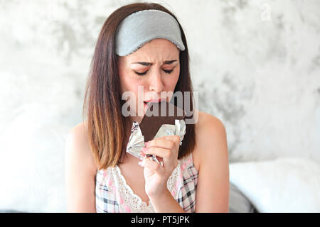 Chocoholic. Fröhliche traurige junge craing Frau Schokolade essen Bar und halten die Augen geschlossen. Stress Konzept Stockfoto