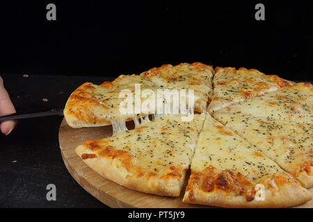 Lecker geschnitten Pizza mit basilikumblätter auf hölzernen gezüchtet. Stockfoto
