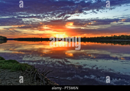 Herbst, einem wunderschönen Sonnenaufgang am Ufer. Helle, schöne Farben in den Morgenhimmel und in der Reflexion im Wasser. Schwerpunkte in den Vordergrund Stockfoto